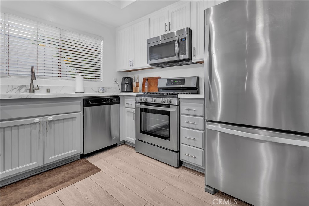 15251 Leffingwell Road, Unit 8 Whittier, CA 90604 - Photo 6 of 26 a kitchen with cabinets stainless steel appliances and wooden floor
