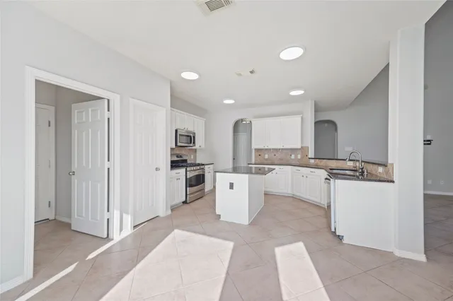 a kitchen with a refrigerator and white cabinets
