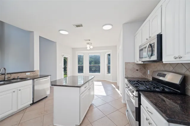 a kitchen with stainless steel appliances granite countertop a sink stove and cabinets
