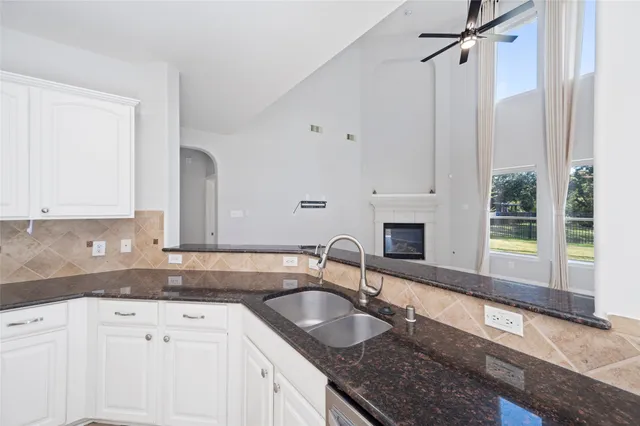 a kitchen with granite countertop a sink a stove and cabinets