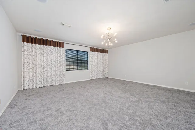 a view of an empty room with a chandelier fan