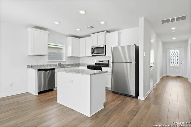 a kitchen with wooden floors white cabinets and stainless steel appliances