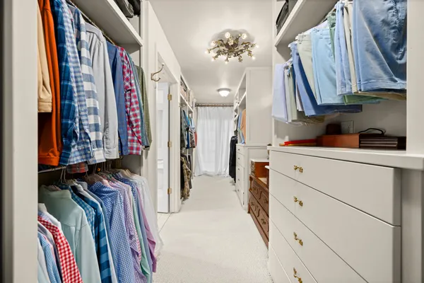 a view of walk in closet with clothes and shoes
