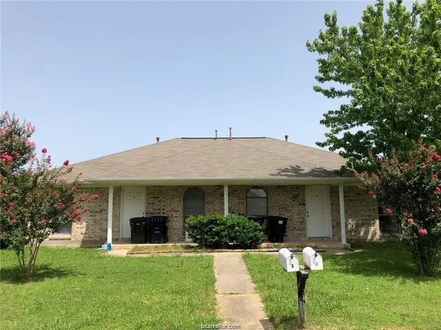 a front view of a house with a garden and trees