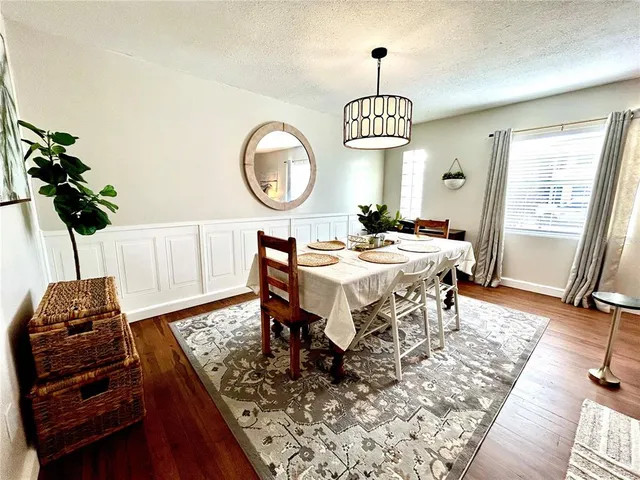 a dining room with wooden floor a chandelier a wooden table and chairs