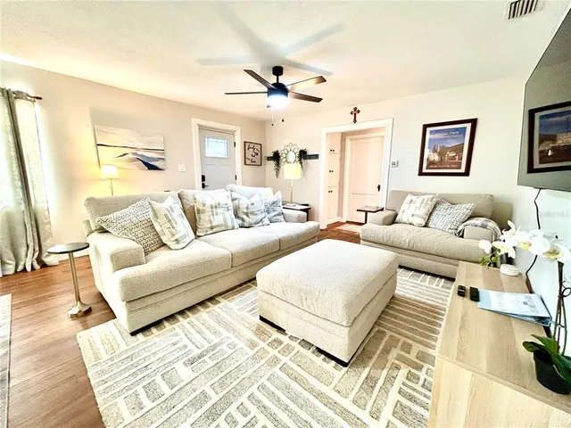 a living room with couches and kitchen view with wooden floor