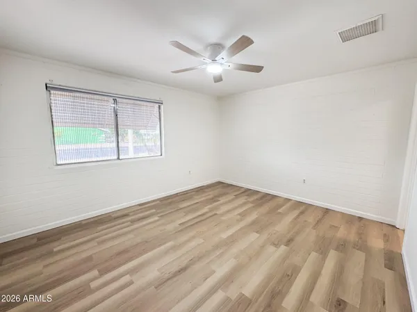 a view of an empty room with wooden floor and a window