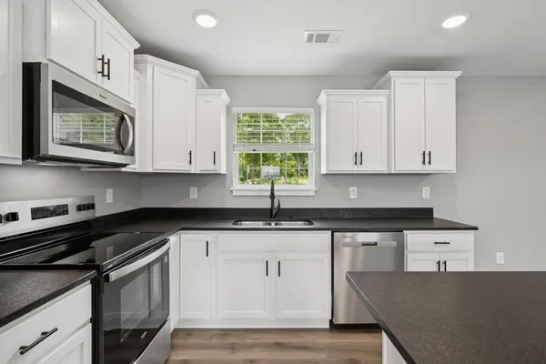 a kitchen with granite countertop white cabinets and white appliances