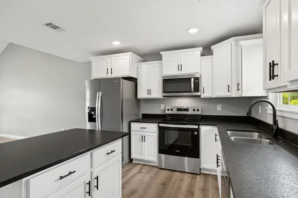 a kitchen with granite countertop white cabinets and stainless steel appliances
