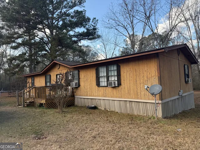a view of a house with a large tree and wooden fence