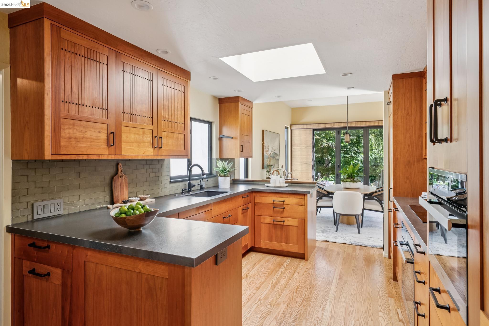576 Vistamont Avenue Berkeley, CA 94708 - Photo 10 of 33 Kitchen featuring warm-toned wood cabinetry with varied panel designs, dark countertops, and a subway tile backsplash