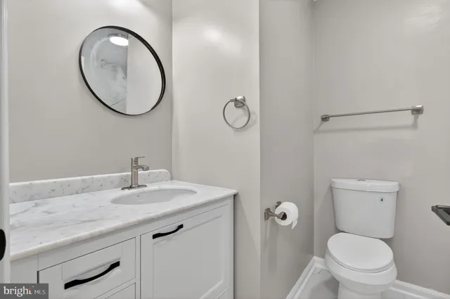 a bathroom with a granite countertop toilet a sink and a mirror
