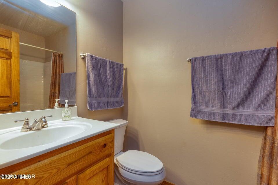 4800 West Tatanka Loop Show Low, AZ 85901 - Photo 19 of 36 a bathroom with a granite countertop toilet sink and mirror