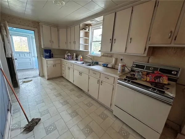 a kitchen with a sink a stove cabinets and a window
