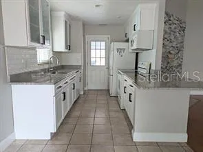 a large white kitchen with cabinets and a outdoor space