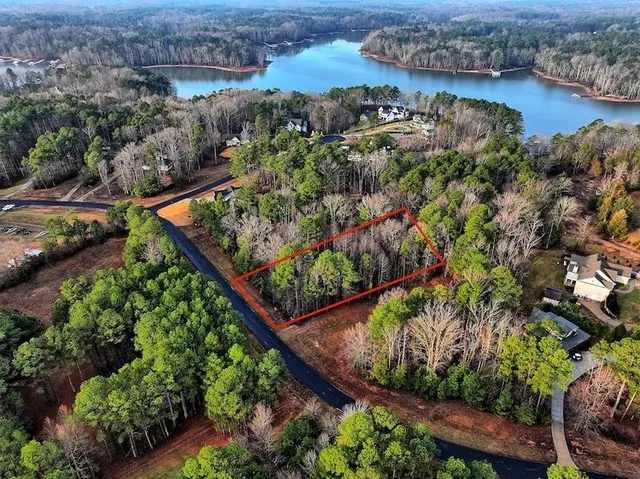 an aerial view of a houses with a yard and lake