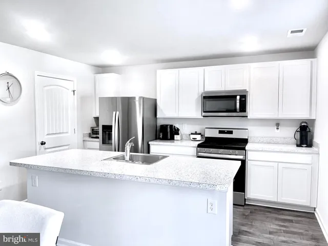 a kitchen with granite countertop a refrigerator stove and sink