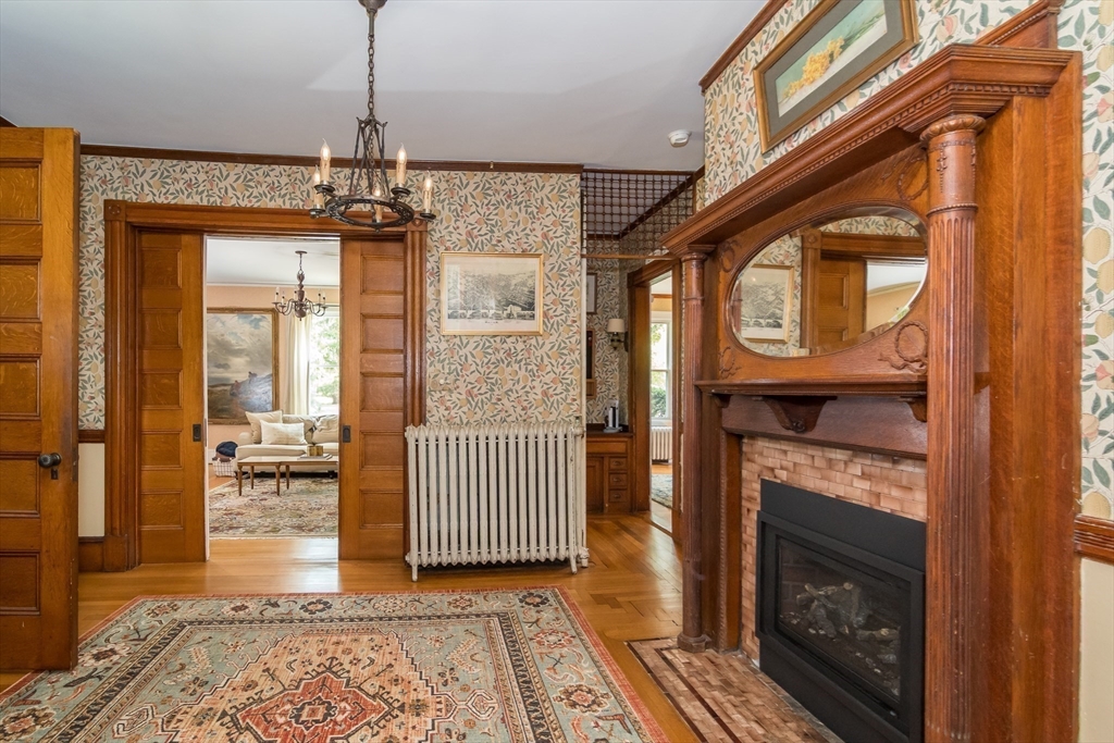 224 Bacon Street Natick, MA 01760 - Photo 6 of 28 a view of a hallway with wooden floor and a chandelier