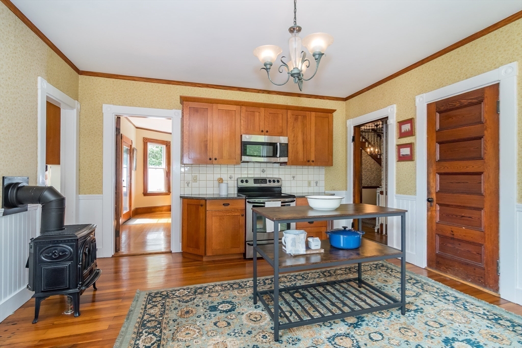 224 Bacon Street Natick, MA 01760 - Photo 9 of 28 a large kitchen with stainless steel appliances granite countertop a stove a sink dishwasher a dining table and chair with wooden floor