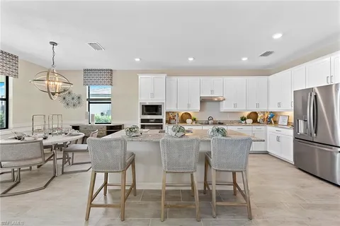 a kitchen with stainless steel appliances granite countertop a stove a refrigerator a kitchen island a dining table and chairs