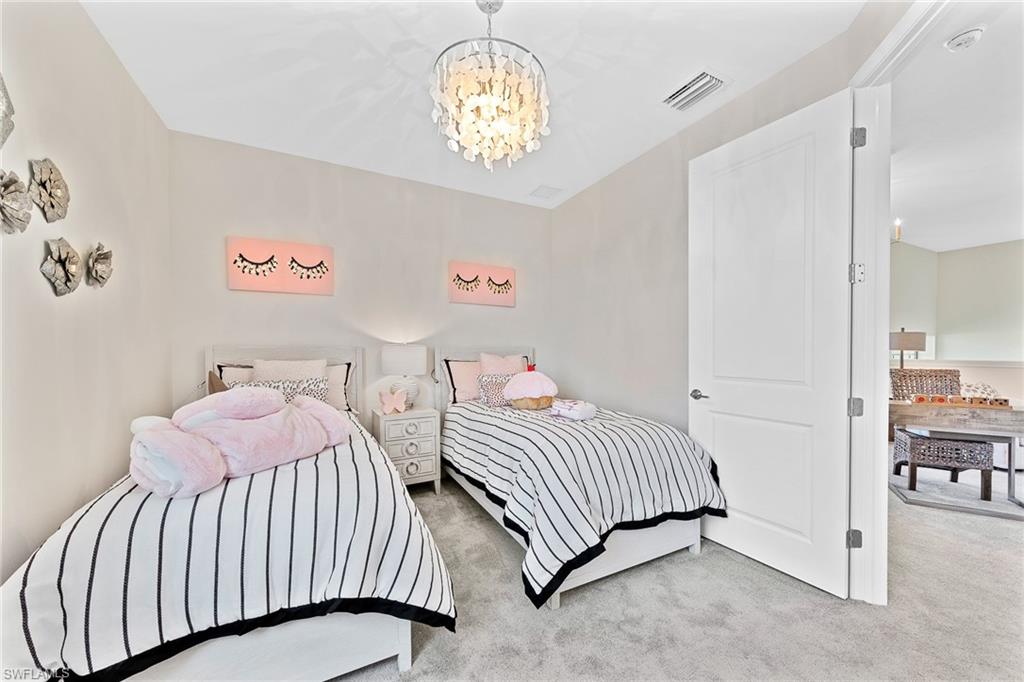 11581 Timber Creek Drive Fort Myers, FL 33913 - Photo 29 of 50 a bedroom with two beds and a chandelier
