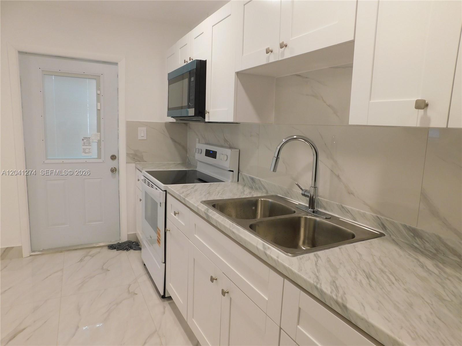 2230 Northwest 58th Street, Unit B Miami, FL 33142 - Photo 7 of 18 a kitchen with stainless steel appliances granite countertop a sink and a white cabinets
