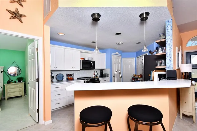 a kitchen with stainless steel appliances a white table chairs and a refrigerator