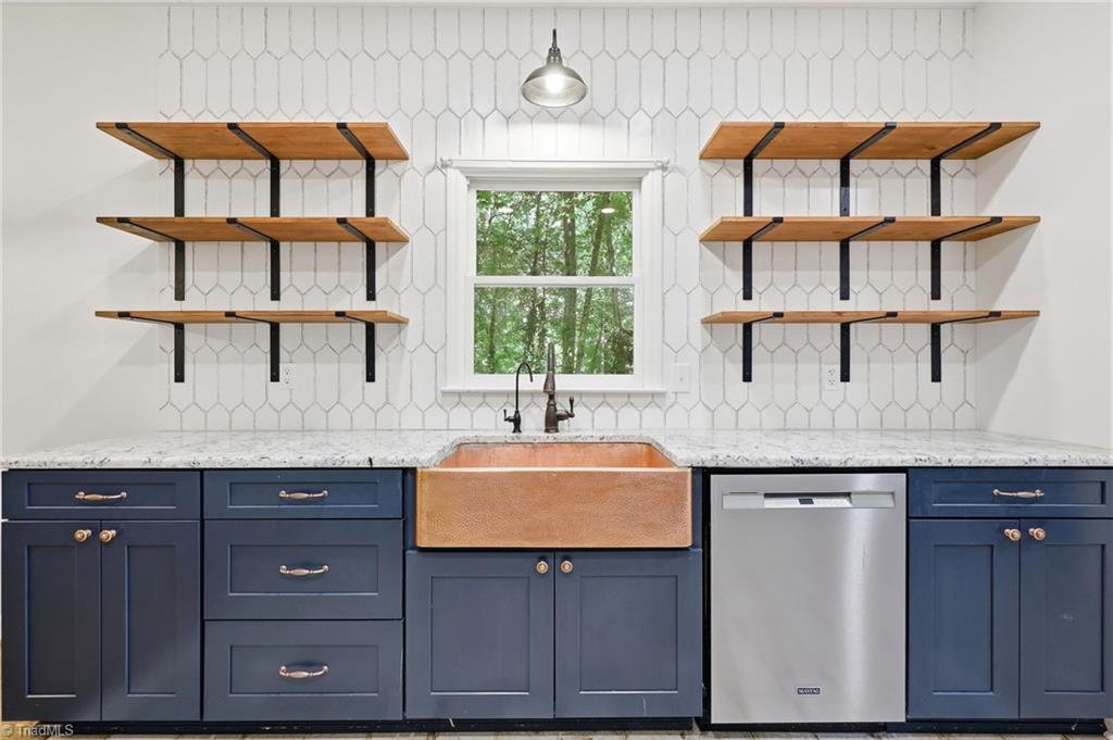 8861 Boylston Road Colfax, NC 27235 - Photo 13 of 50 Designer details shine with a hammered copper farmhouse sink, upgraded countertops, statement tile backsplash, and custom floating wood shelves.