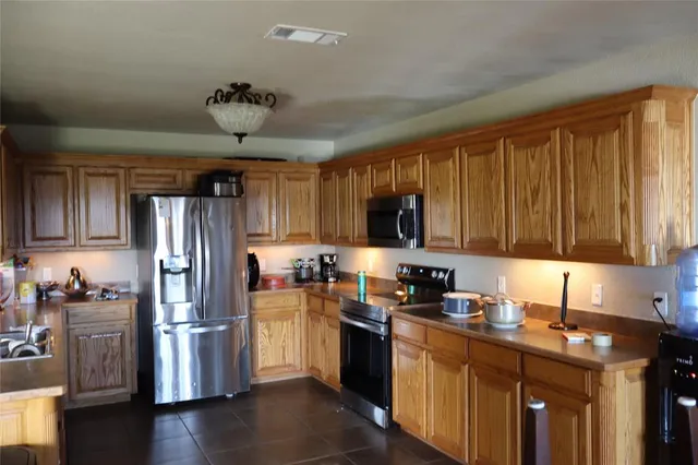 a kitchen with stainless steel appliances granite countertop a refrigerator a sink a stove a microwave and wooden cabinets