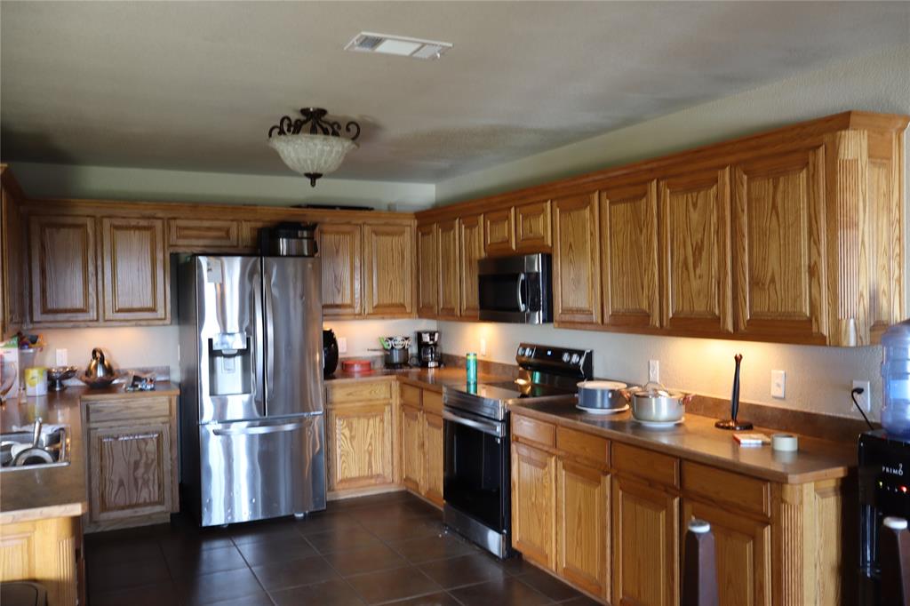 902 El Campo Drive Rio Vista, TX 76093 - Photo 4 of 11 a kitchen with stainless steel appliances granite countertop a refrigerator a sink a stove a microwave and wooden cabinets
