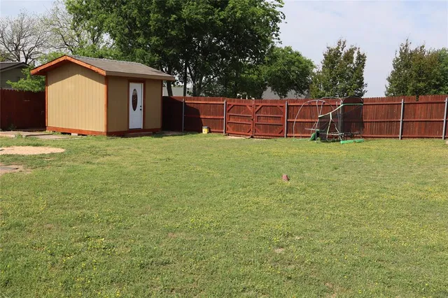 a view of backyard with wooden fence and large trees