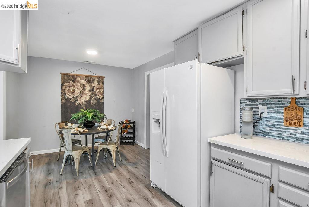 2191 East Cypress Road Oakley, CA 94561 - Photo 10 of 48 Kitchen with white fridge with ice dispenser, stainless steel dishwasher, backsplash, light wood finished floors, and white cabinetry