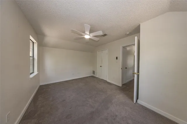 an empty room with a ceiling fan and a window