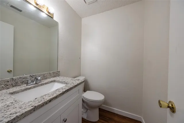 a bathroom with a granite countertop sink and a toilet