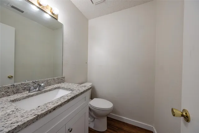 a bathroom with a granite countertop sink and a toilet