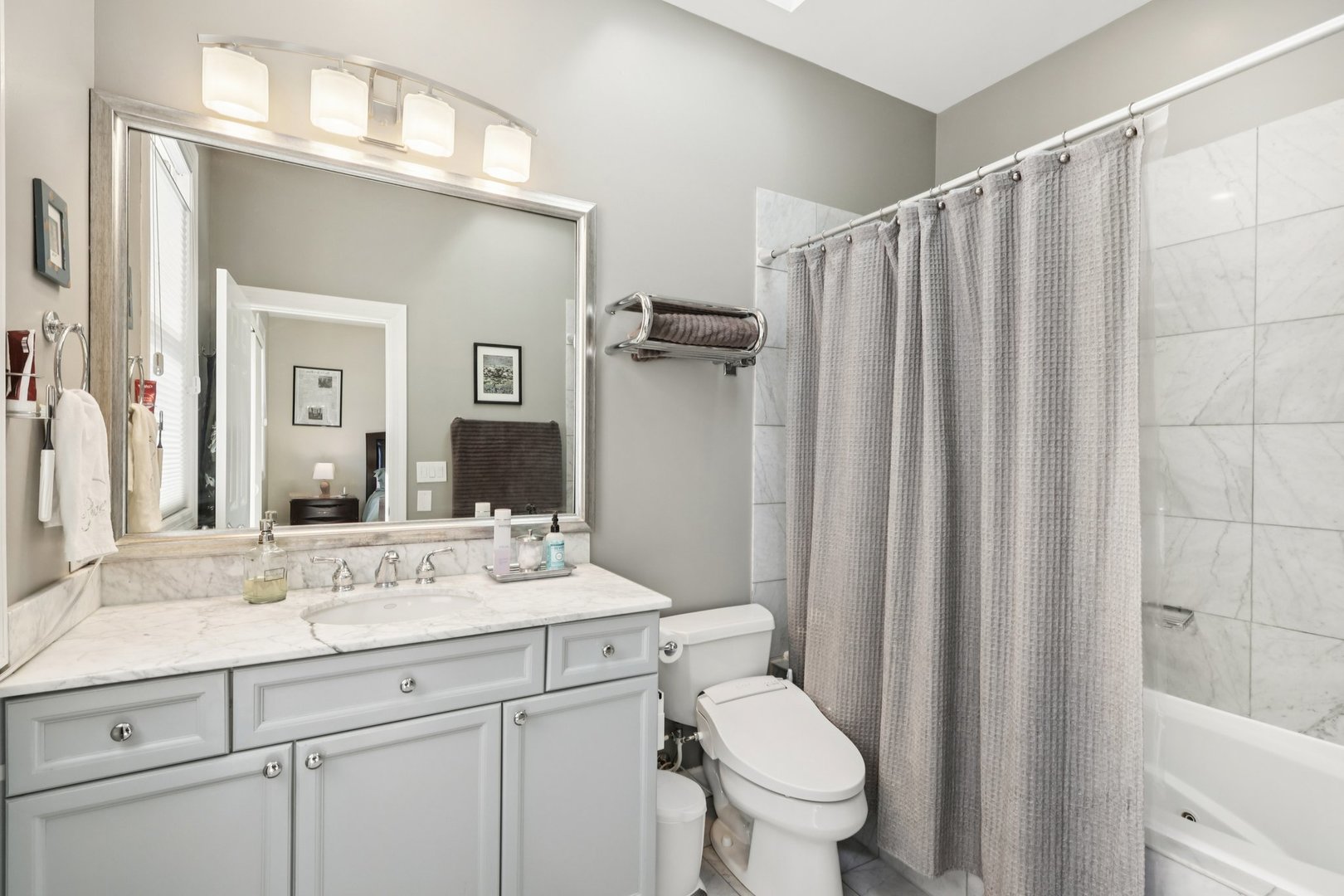1473 West Irving Park Road, Unit 4E Chicago, IL 60613 - Photo 23 of 44 a bathroom with a sink a toilet a mirror and shower curtain