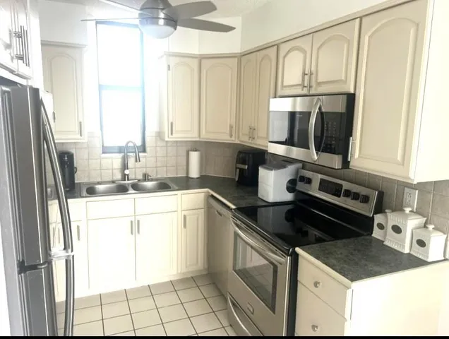 a kitchen with kitchen island granite countertop a sink appliances cabinets and a counter top space