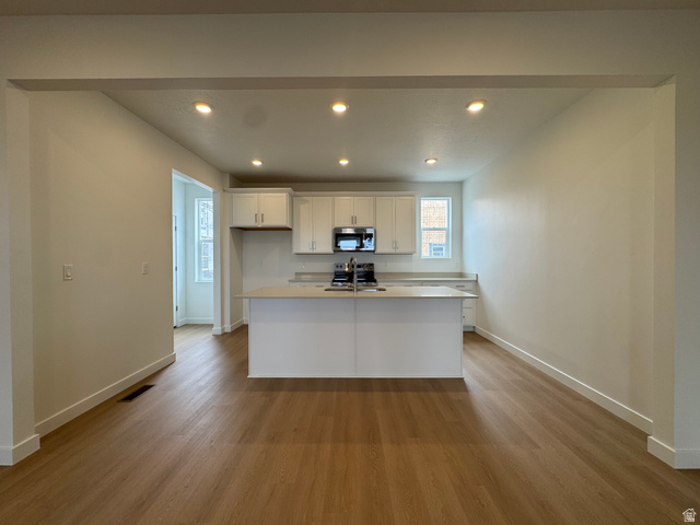 1876 West 1575th North, Unit 237 Layton, UT 84041 - Photo 4 of 20 Kitchen featuring white cabinets, recessed lighting, an island with sink, dark wood-type flooring, and range with electric stovetop