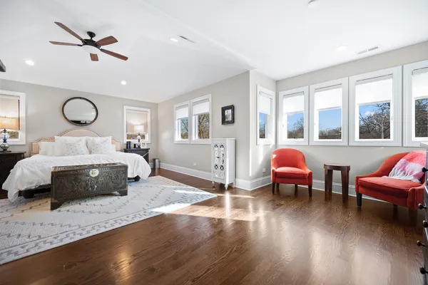 a bedroom with a bed a couches and a large window with wooden floor