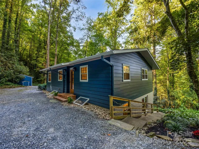 a view of a house with a yard and large trees