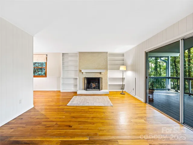 a view of empty room with floor to ceiling window and fireplace