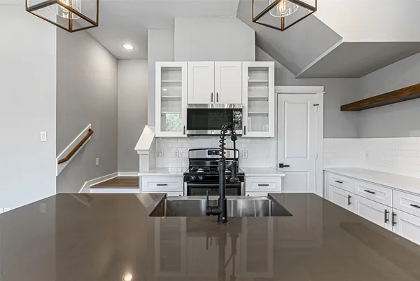 a kitchen with stainless steel appliances a stove a sink and a white cabinets