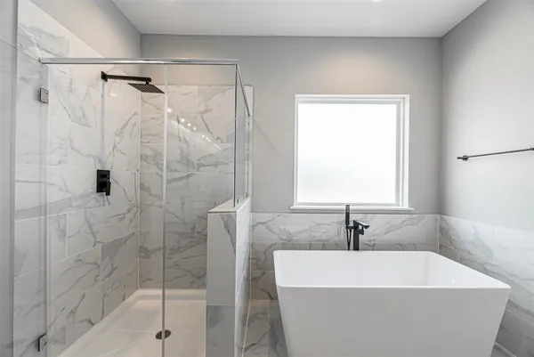 a bathroom with a white bath tub a shower and a sink