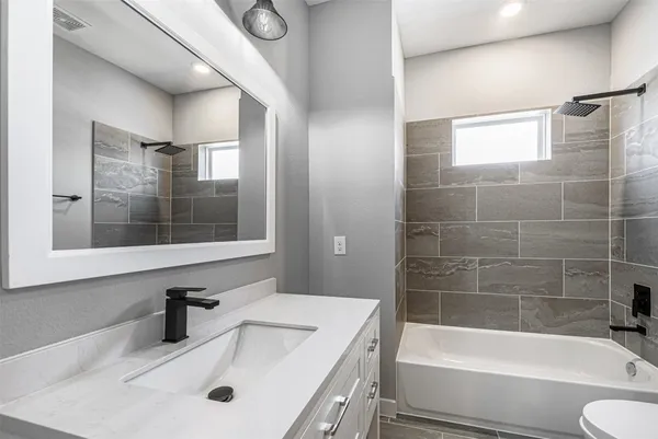 a bathroom with a tub sink toilet and a mirror
