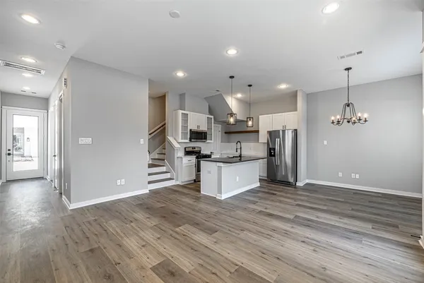 a large kitchen with stainless steel appliances kitchen island a large counter top and wooden floors