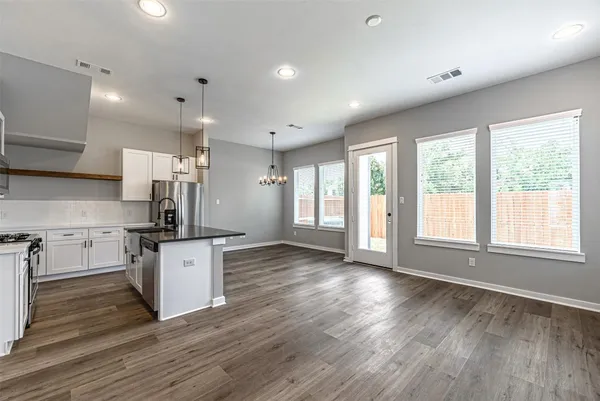 a kitchen with stainless steel appliances granite countertop a stove top oven a sink and a refrigerator