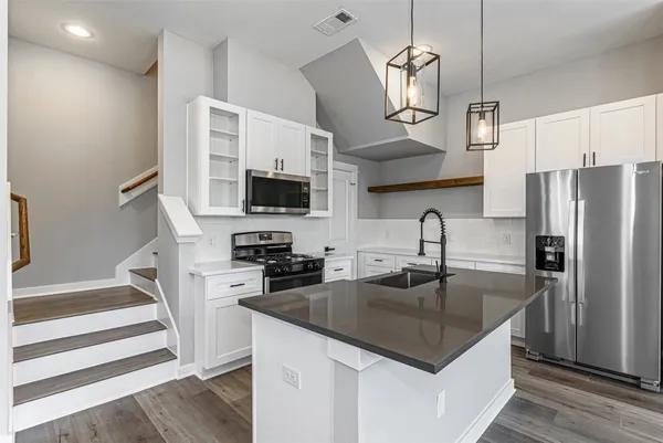 a kitchen with stainless steel appliances granite countertop a sink a microwave a refrigerator and wooden cabinets