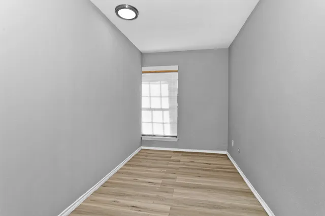a view of an empty room with wooden floor and closet