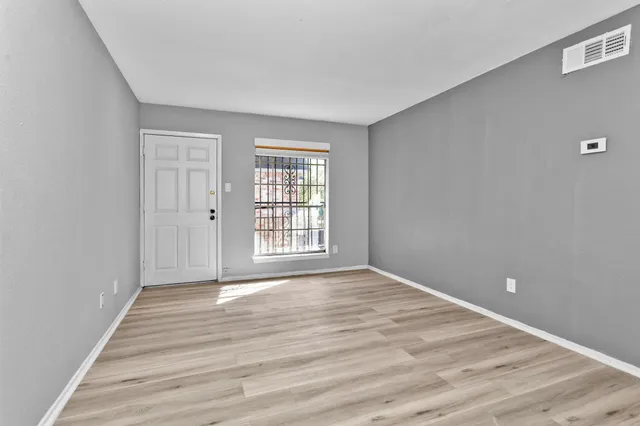 a view of an empty room with wooden floor and a window