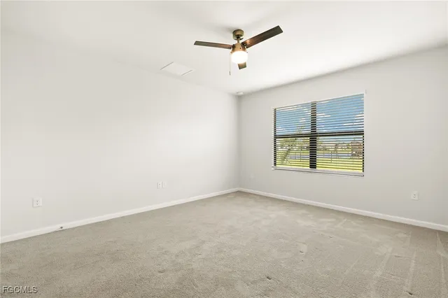 an empty room with ceiling fan and window